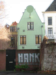 828577 Gezicht op het lichtgroen geschilderde pand Strosteeg 6 te Utrecht, met op de tuinmuur graffiti met de tekst 'HANK'.